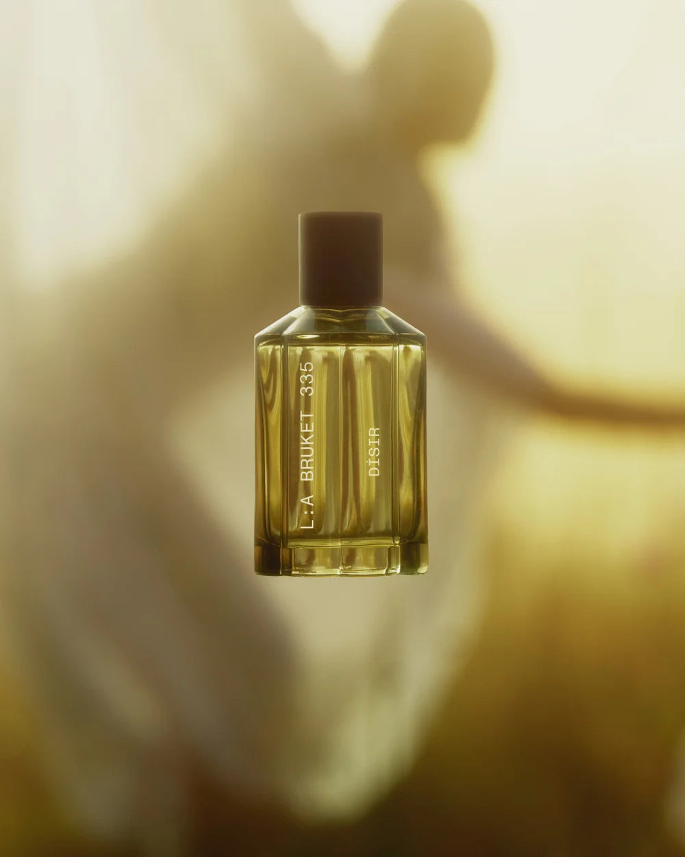 Gelbgrüner Dísir Parfumflakon zwischen goldenen Bewegungen