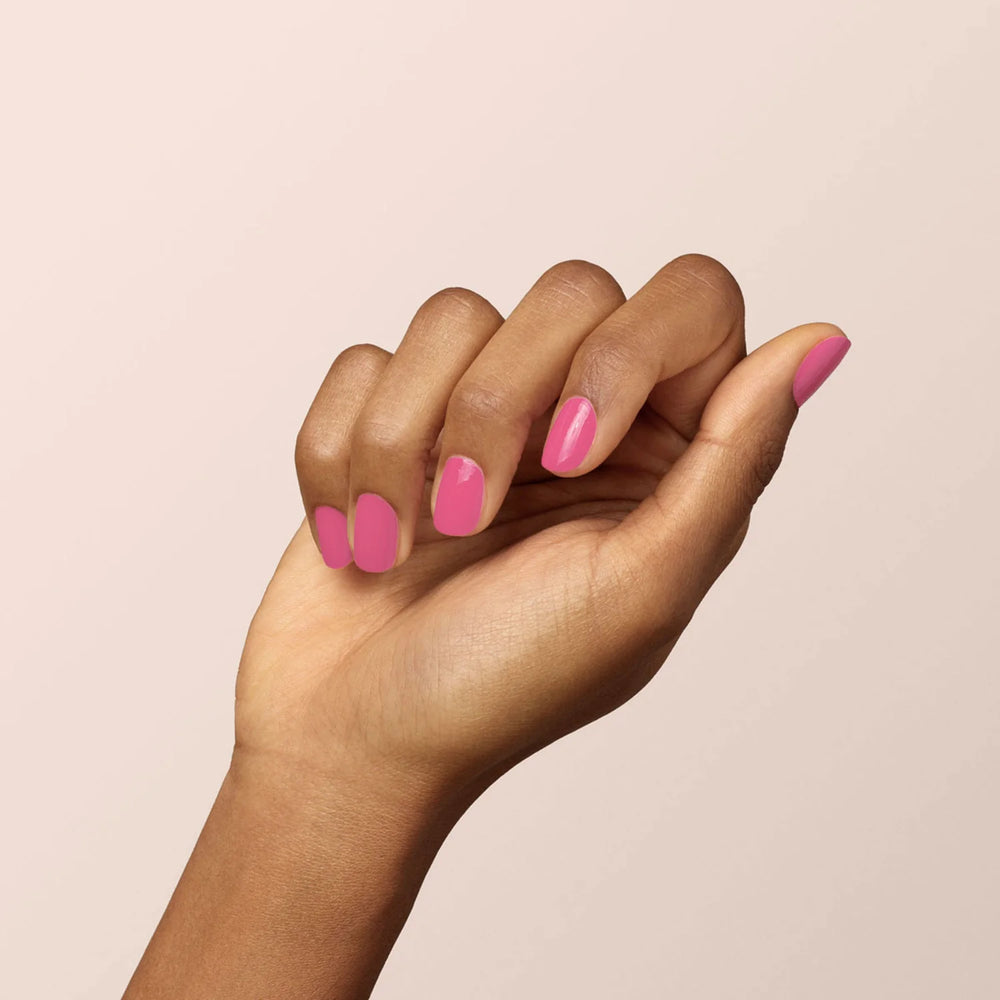 Hand zeigt leuchtend pink maniküre Nägel in Manucurist Rose-Ton vor neutralem beigem Hintergrund mit glänzendem Finish