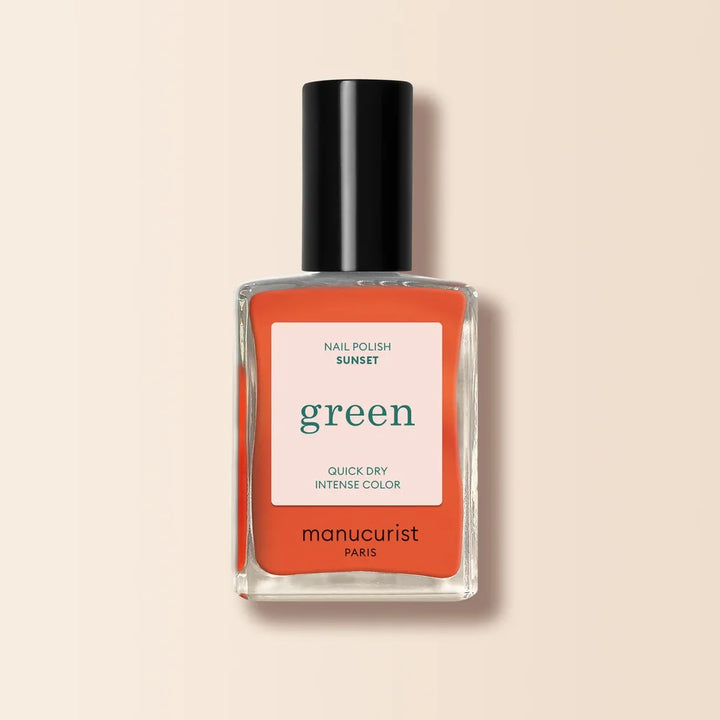 Manucurist Paris Green Nagellack in Sunset - leuchtend korall-oranger Farbton in Glasflasche mit schwarzem Verschluss auf neutralem beigem Hintergrund