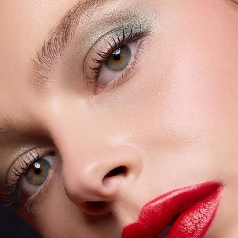 Nahaufnahme eines Models mit betonten Wimpern, schimmerndem Augen-Make-up und roten Lippen