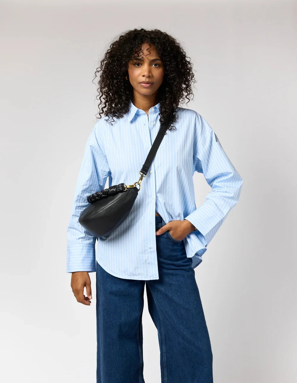O My Bag Leo Midi Twisted als schwarze Crossbody Bag zum hellblauen Hemd getragen